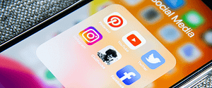 Ecran de téléphone sur plusieurs logo d'application de réseaux sociaux : Pinterest, Instagram, Youtube, Twitter, Clubhouse et Facebook