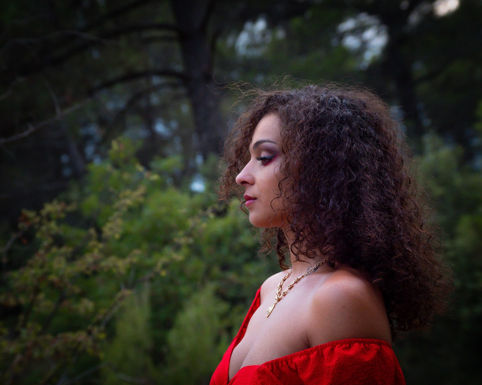 Une femme de profil dans une forêt avec un haut ouvert rouge